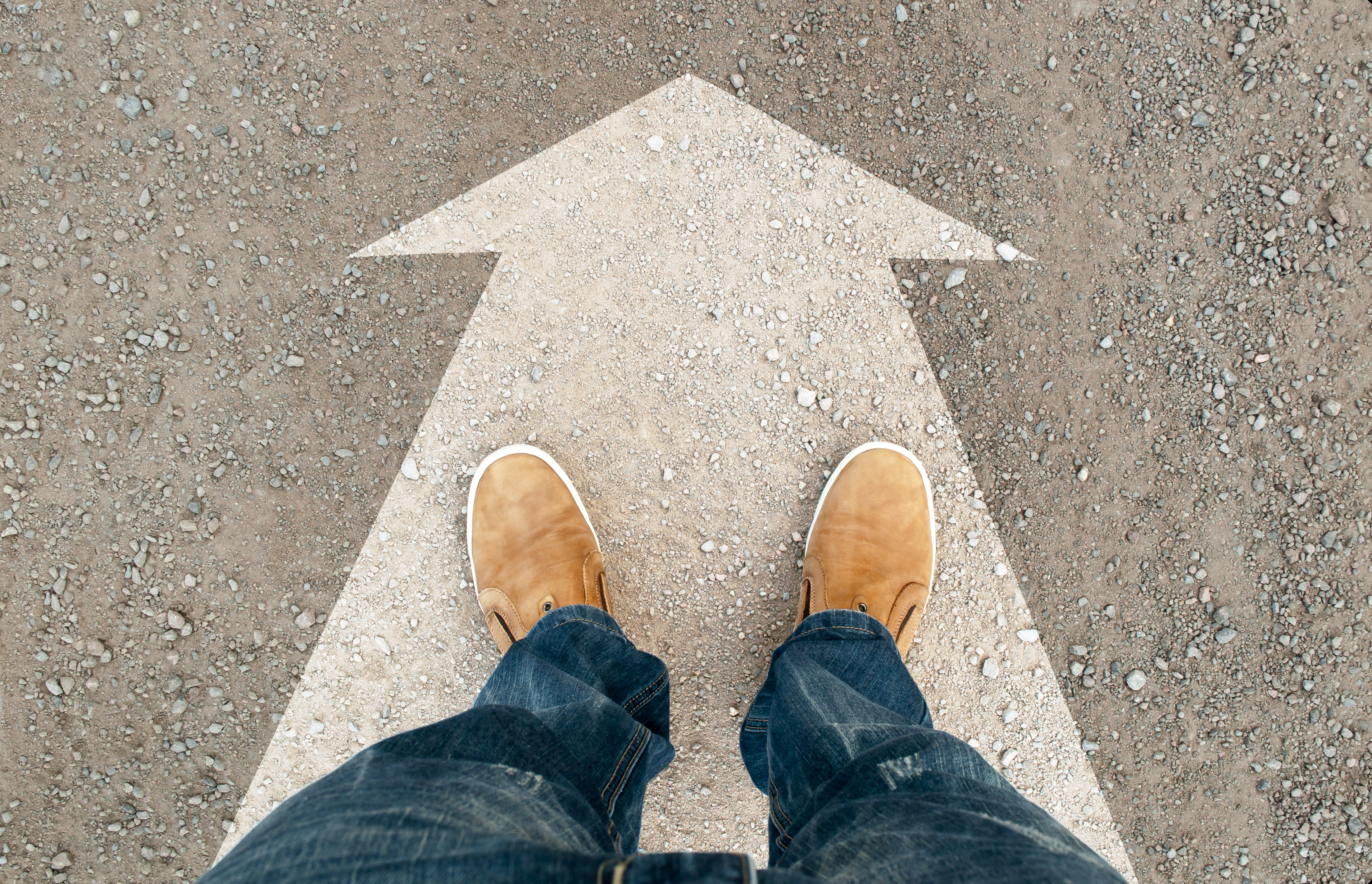 yellow boots on the road. a man standing on the road. the road arrow